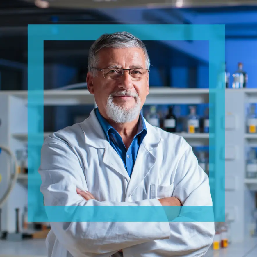 A man in a lab coat stands confidently in front of a blue frame, showcasing a professional laboratory environment.